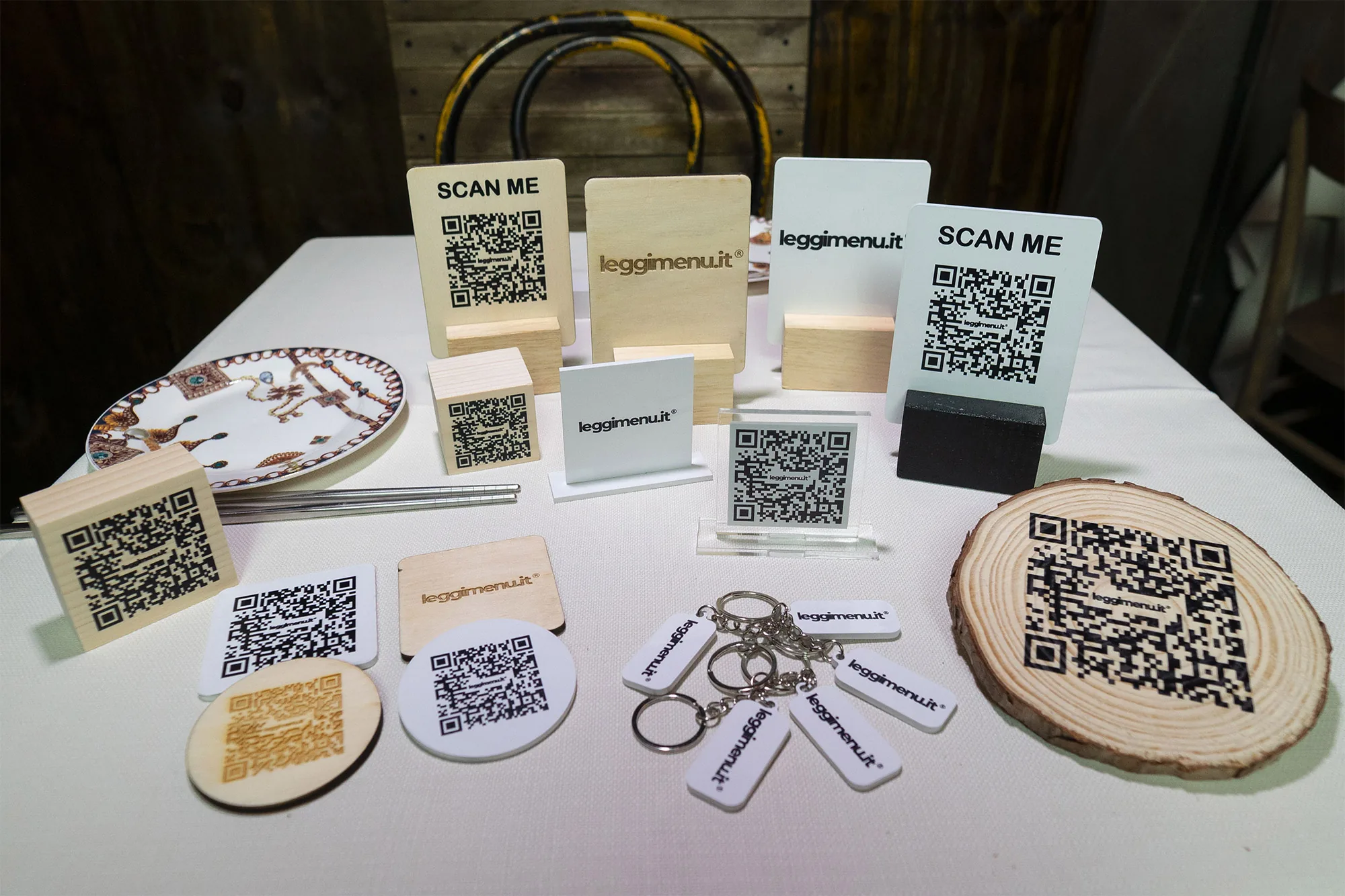 Carrellata di supporti fisici malifactory con il QR Code di leggimenu: espositori da tavolo in legno e PVC, targhette, portachiavi e adesivi